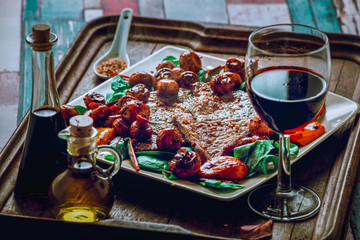 cooked steak on plate with salad and glass of wine .
