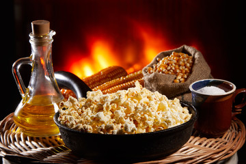 Appetizing salted popcorn with cheese. Heap of homemade delicious popcorn on a rustic wooden table. Snacks and food for a movie theater or cinema. Fastfood background. Frying pan with corn and oil. .
