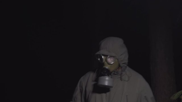 man in a gas mask escapes from coronavirus in the woods at night