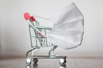 Shopping trolley with medical mask. Coronavirus pandemic, COVID-19 shopping concept