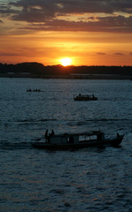 Silhueta de barcos atravessando rio durante o pôr-do-sol em Marabá