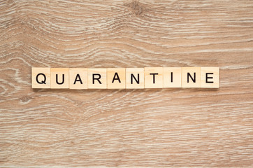 The word "Quarantine" spelt out with letter tiles on the wooden background