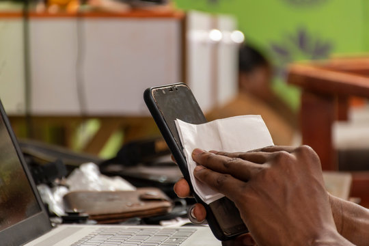 black man cleaning the surface of his mobile phone with a tissue
