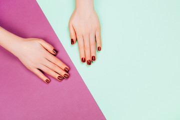 Woman hands with dark red manicure on background divided on two parts with place for text. Flat lay style.