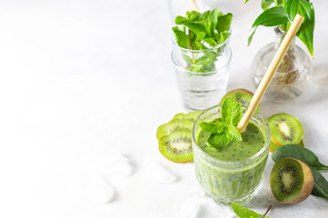 Detox green smoothie - kiwi, spinach and matcha on a light grey slate, stone or concrete background.