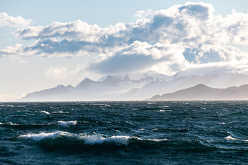 Wellen auf dem Meer in der Antarktis mit der Küste im Hintergrund, Wolken und Eis der Gletscher 