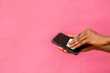 black man cleaning the surface of his mobile phone with a tissue