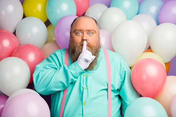 Hush be voiceless. Serious man big abdomen put finger lips mouth ask dont tell say speak talk private anniversary gift wear turquoise pink suspenders on air balls baloons background
