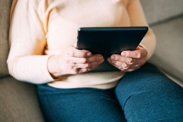 Obraz premium Old woman hands using a tablet. Old people with technology concept