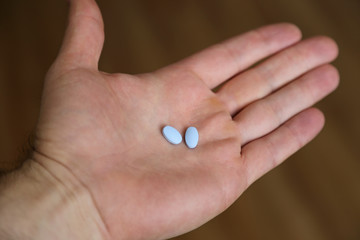 Two generic naproxen sodium pills, used as a nonsteroidal anti-inflammatory painkiller drug (NSAID), are shown held in a hand.