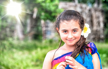 Travel and holiday concept. Young girl wearing tropical flower on the beach with forest background