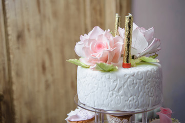 Luxurious pink wedding cake with flowers. Birthday, Valentine's day cake. Cupcakes  with pink roses. Wooden background