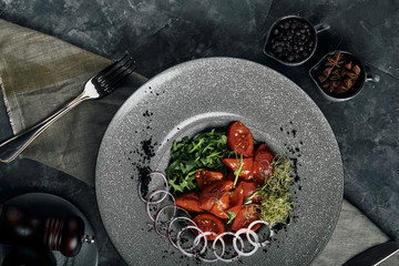 Salad with arugula and fresh pickled tomatoes and onions. Beautiful serving, traditional Italian cuisine, gray background, copy space. food concept