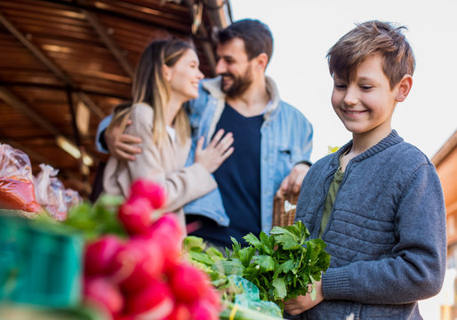 Family Buying Fresh Vegetables At Farmers Market Stall