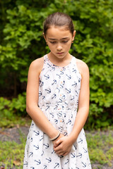 Fototapeta premium Young girl looking down holding her hands feeling sad.