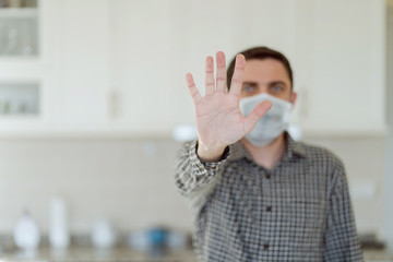 stop coronavirus symbol, man's hand and face with medical mask on background.