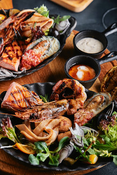 Assorted seafood on plates. Beautiful composition on a served seafood table, squid, shrimp, salmon steak and octopus. Food photo, low key, traditional Italian cuisine. Top view, save the space