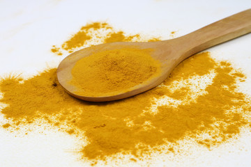 Turmeric powder in a wooden spoon isolated on a white background is an ingredient in turmeric foods and ingredients in skin care products. Turmeric helps the skin to be strong.
