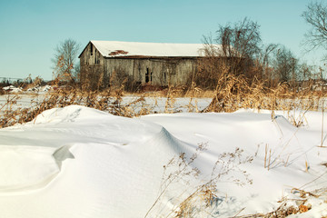 Barn on a snowy day with snow banks in the foreground.