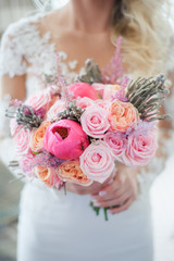 Naklejka premium White, beige, pink flowers. Bride holding bouquet. Close-up and selective focus. Beautiful bouquet of roses, peonies with ribbons in the hands of the bride, wedding details