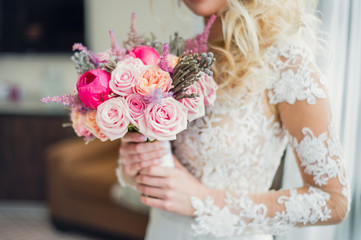 White, beige, pink flowers. Bride holding bouquet. Close-up and selective focus. Beautiful bouquet of roses, peonies with ribbons in the hands of the bride, wedding details