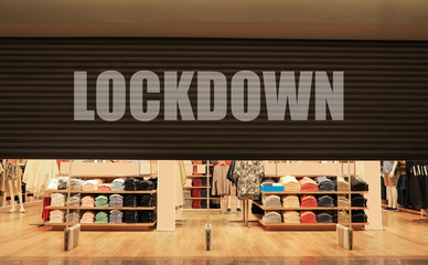 A roller shutter of a departmental store half close and a lockdown message.  A conceptual idea on...