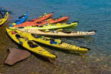 Red, blue,yellow sea kayaks closeup view on rocky beach