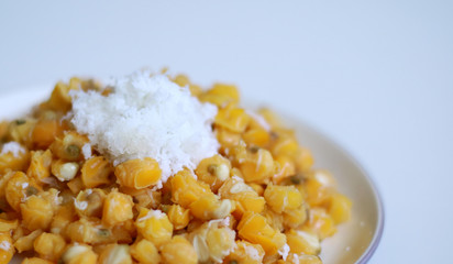 Grontol jagung on white background.  Grontol jagung is traditional snacks in Indonesia. Boiled shelled corn sprinkled with grated coconut.