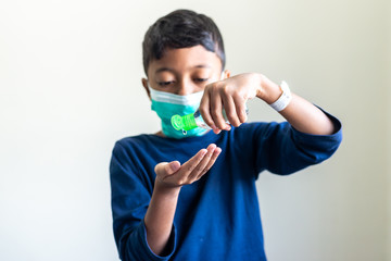 Sick Muslim Kid with surgical mask squeezing hand sanitizer onto his hand. Precaution during Covid-19 Coronavirus scare. Shallow depth of field