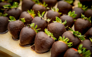 Close up of group of strawberries covered in dark chocolate  aranged in diagonal rows at catered party