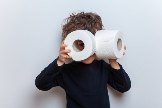 a little boy a child holds two rolls of toilet paper in his hands depicting binoculars or glasses.