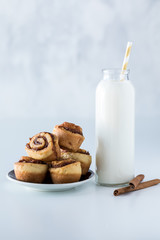 A close up of a bottle of milk with a small plate of mini cinnamon buns ready for eating.