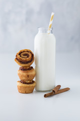 A bottle filled with milk served with three mini cinnamon buns for snacking.