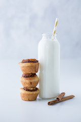 A close up of a bottle of milk with three mini cinnamon buns ready to eat.