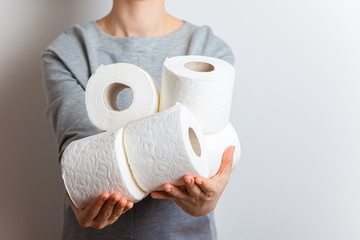 The girl holds out her hands full with toilet rolls.