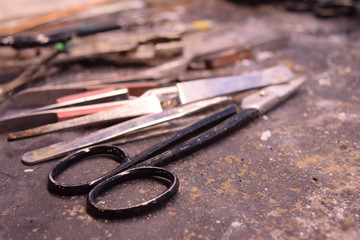 Scissors, Tweezers, File and other Tools Spread out over a Old Messy Wood Work Bench