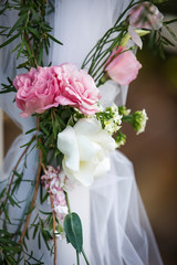 Pink and white roses tied to a tulled wedding post