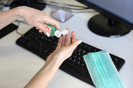 Female Hands Squeeze A Sterilizing Gel From Bottle On Keyboard Background. Hand Disinfection At The Workplace In The Office. Virus Protection