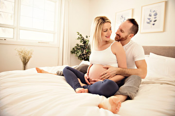Fototapeta na wymiar Beautiful pregnant woman and her handsome husband spending time together in bed