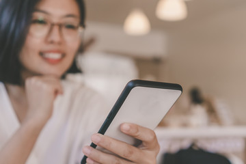 Woman feel happy and smile while using smartphone to do work business, social network, communication in public cafe work space.