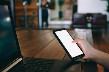 Woman hand using laptop or smartphone to work study on work desk with clean nature background background. Business, financial, trade stock maket and social network.