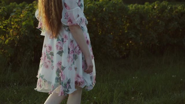 Young ledy in dress walks barefoot on the grass on nature