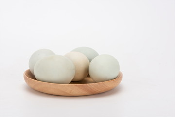 A few duck eggs are placed on a wooden plate, isolated against a white background
