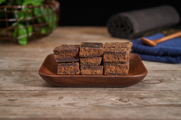 Brown sugar is placed in a wooden plate against the backdrop of a vintage old wooden board. Red ginger sugar blood food