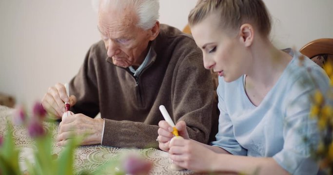 hands coloring easter eggs with colors and brush.