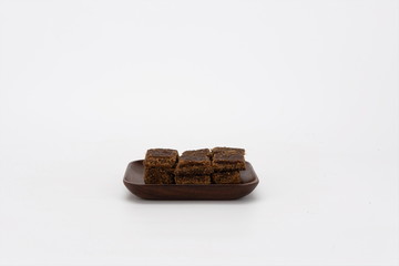 Brown sugar is placed in wooden plates, isolated on a white background. Red ginger sugar is a blood tonic food. It is made by pressing and boiling sugarcane