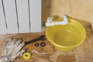 Gloves and repair tools near a leaking heating system. Accident of the heating system of a private...