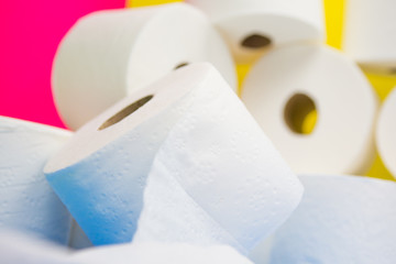 Many toilet paper rolls at home of hoarder on yellow blue pink color background hoarding amid panic buying for corona virus outbreak shortage.