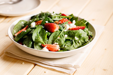 Healthy vegetable salad of fresh spinach, strawberries, feta cheese and almond on plate.
