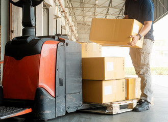 Worker courier lifting package boxes stack on pallet, forklift pallet jack, warehouse delivery service shipment goods © Siwakorn1933